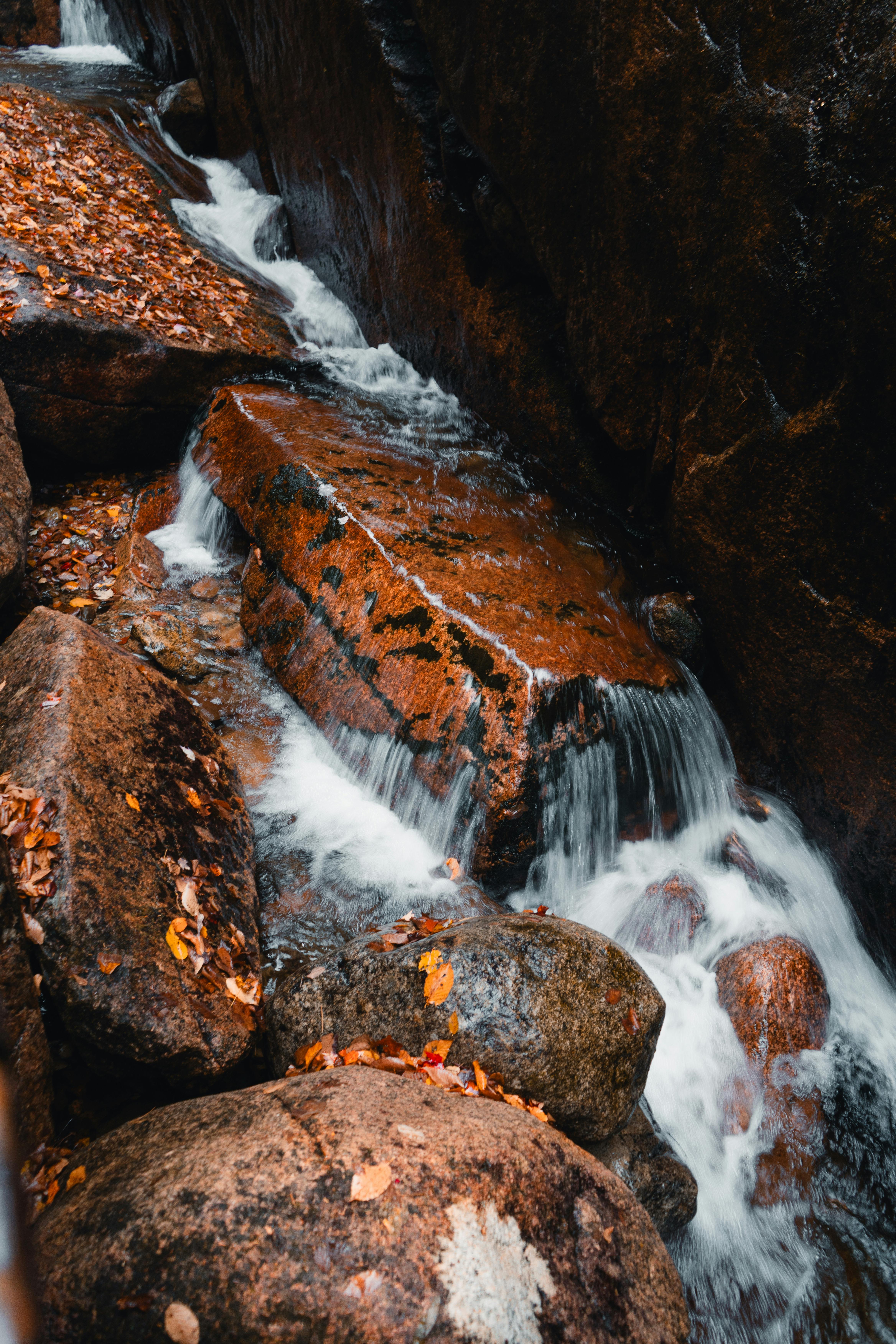 A tranquil small waterfall flowing over rocks surrounded by autumn leaves in Lincoln, NH.
