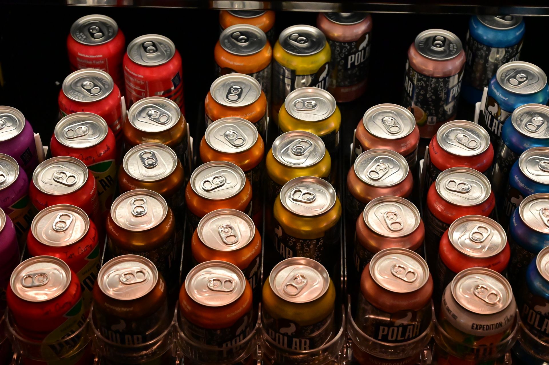 Top view of colorful beverage cans arranged neatly in a vending display.