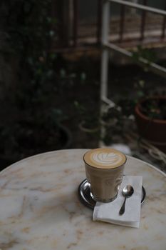 A beautifully crafted latte with foam art on a marble table in a cozy café setting.
