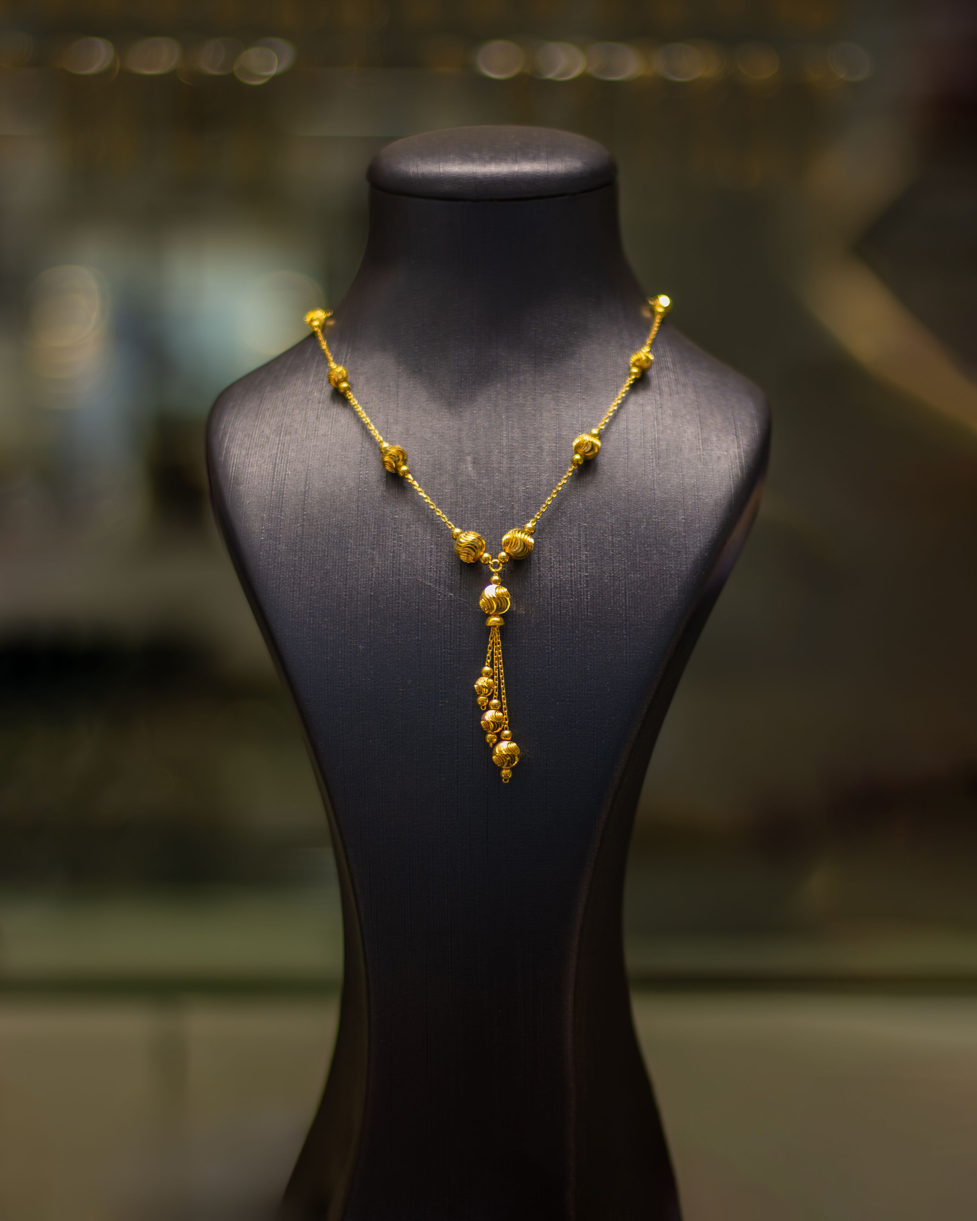 Colar de ouro luxuoso elegantemente exibido em um manequim preto em uma joalheria.