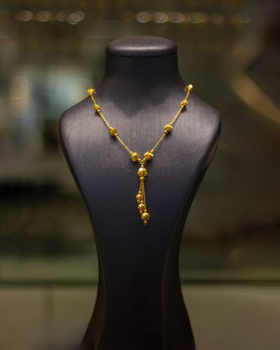Gold beaded necklace on a display bust — photo by Vedat Kandemir on Pexels