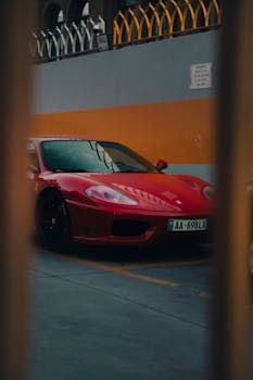 Luxurious red sports car parked in an urban environment under nighttime lighting.