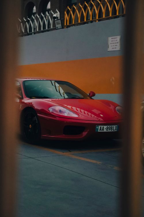 Free Luxurious red sports car parked in an urban environment under nighttime lighting. Stock Photo