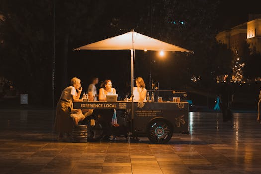 Nighttime street scene showcasing a food stall with visitors in Tirana, Albania.