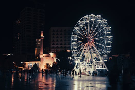 Vibrant night scene of a lit Ferris wheel and clock tower in Tirana, Albania.