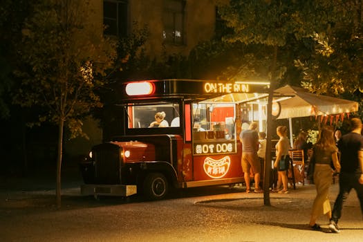 Vibrant night scene of a street food truck serving hot dogs in Tiran, Albania.