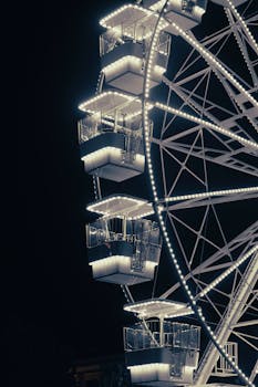 A brightly lit Ferris wheel against the night sky in Tirana, showcasing modern design and vibrant lights.