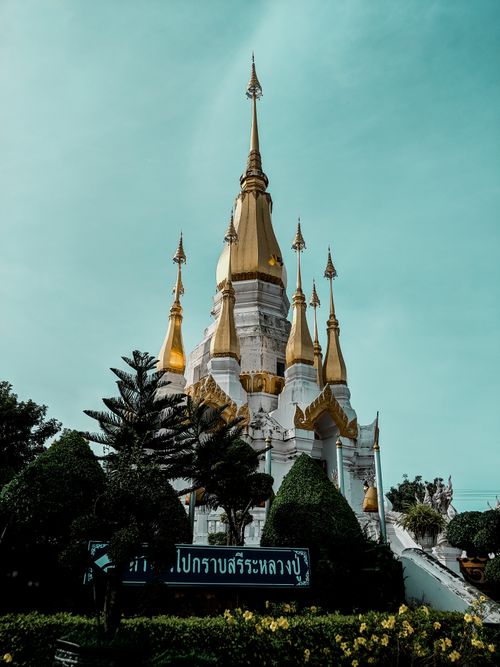 Free A stunning Buddhist temple with golden spires under a clear sky, surrounded by manicured gardens. Stock Photo