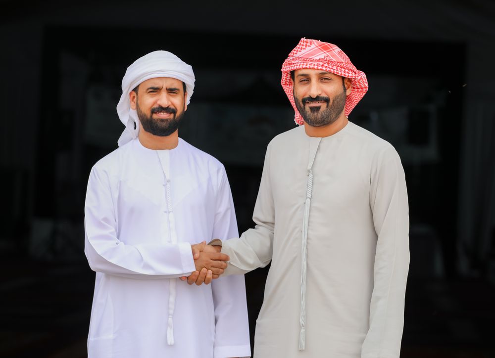 Business handshake in traditional Emirati attire, representing MPMS's partnership with clients in Dubai