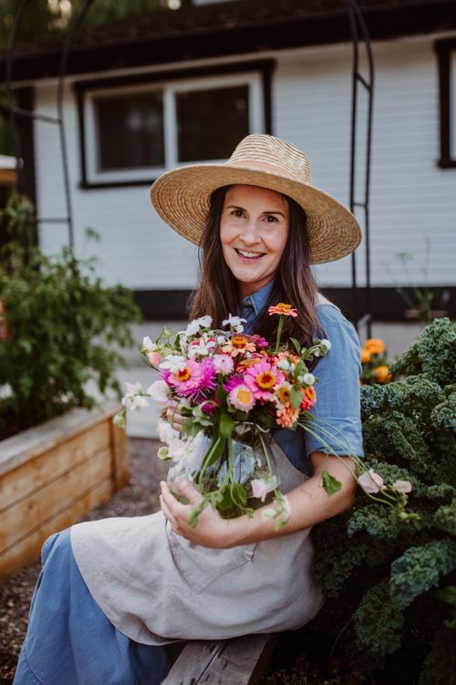 Free Happy woman in sun hat holding a colorful bouquet in a vegetable garden. Stock Photo