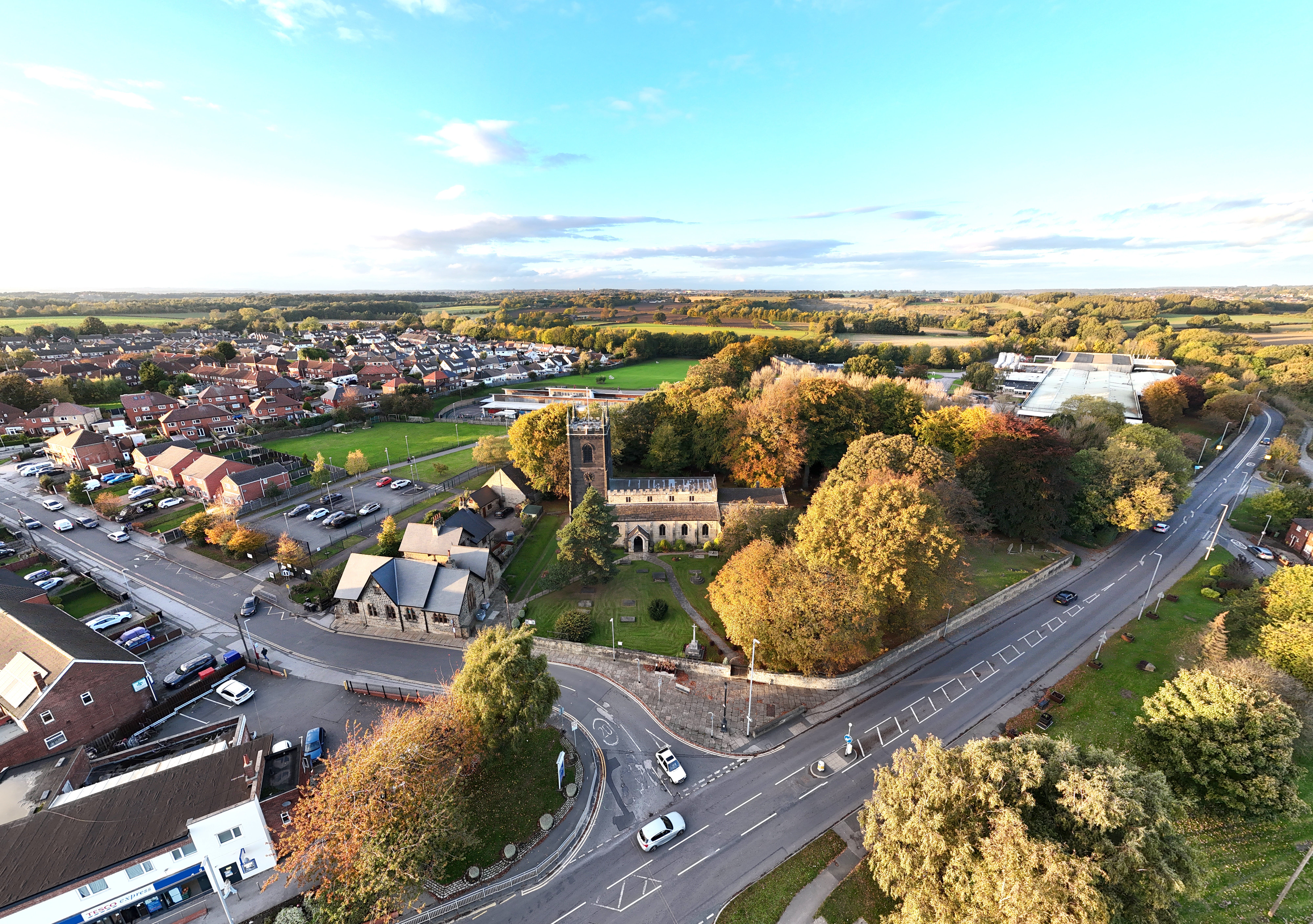 Aerial shot of St Mary's Church and surrounding Swillington, England, showcasing vibrant autumn colors.