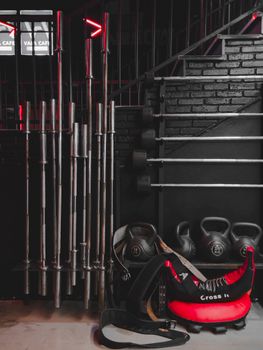 Barbells, kettlebells, and equipment in a modern industrial gym setting.
