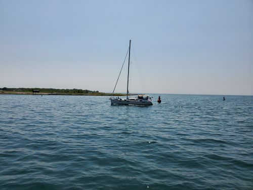 Free Peaceful scene of a sailboat gliding on calm ocean waters under a clear blue sky. Stock Photo