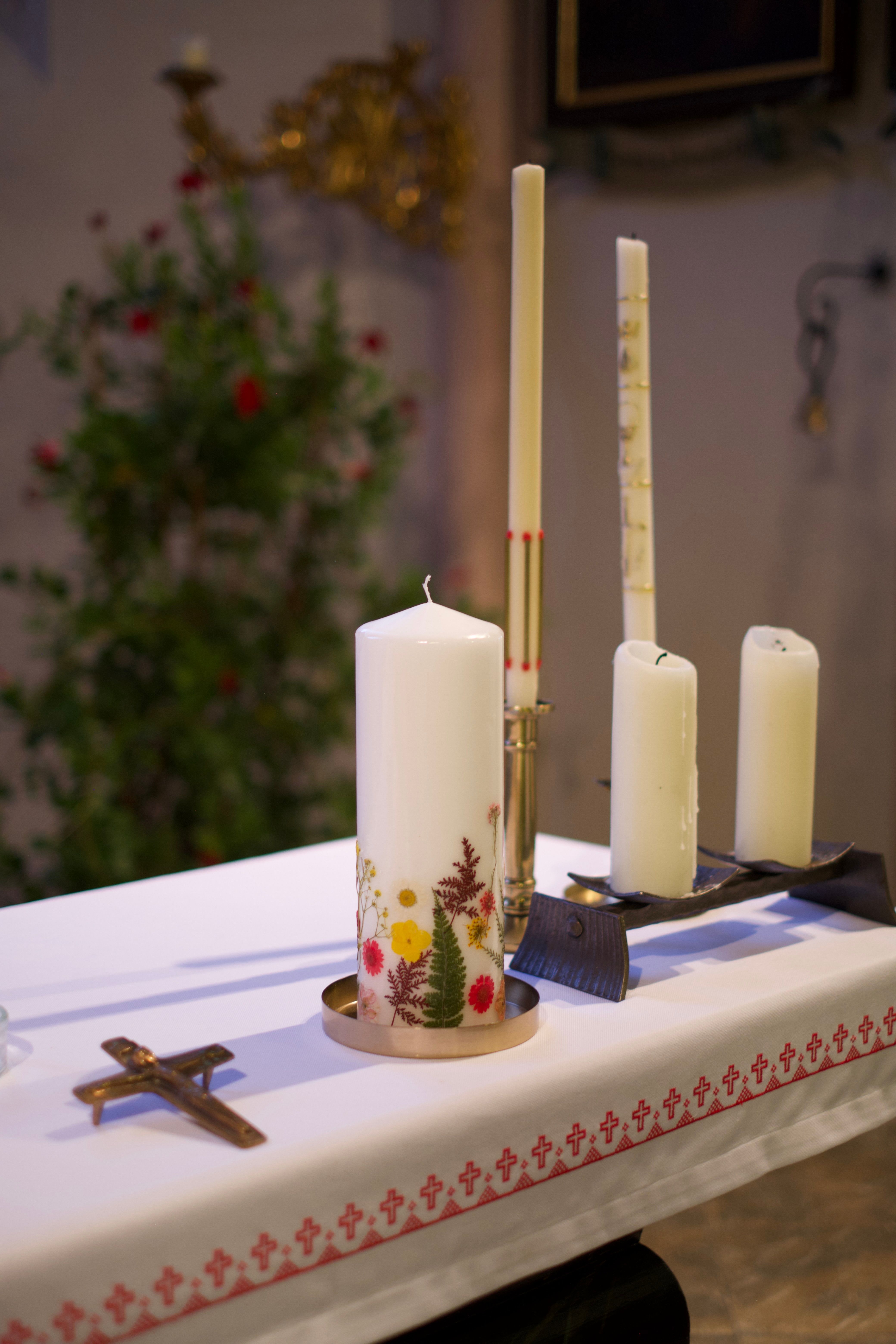 Altar de biserică ortodoxă decorat cu lumânări și aranjamente florale