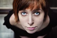 工作室里，一位蓝眼睛、红棕色头发的年轻女子肖像特写引人注目