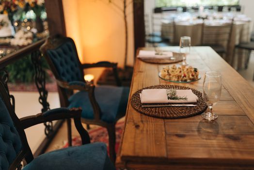 A sophisticated indoor dining setup with blue velvet chairs and wooden table decor.