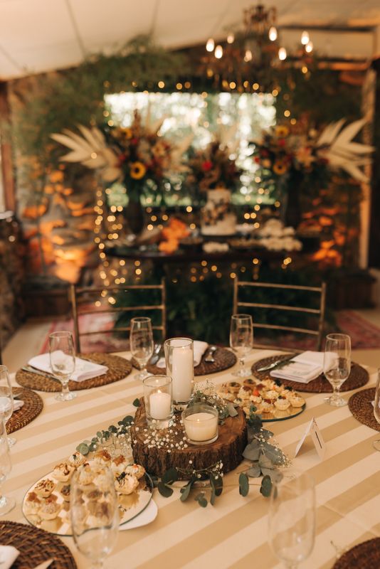 Elegant rustic fall wedding reception table with warm candlelight, string lights, and autumn floral arrangements