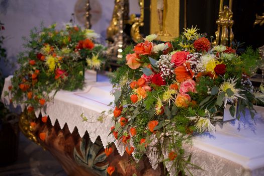 Colorful floral arrangements displayed on an ornate altar indoors, perfect for festive or religious occasions.