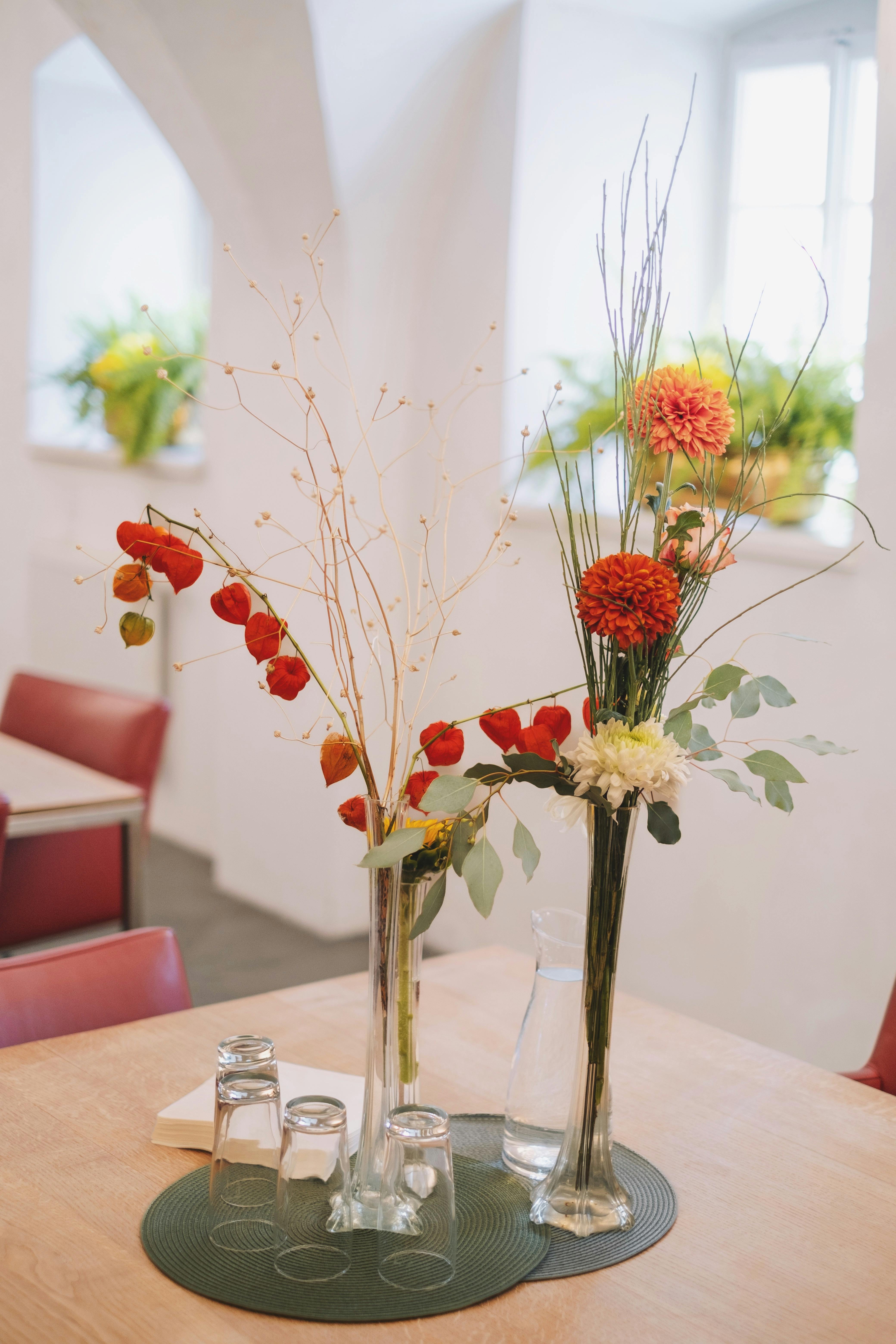 A chic floral arrangement on a table inside a modern cafe, featuring vibrant red and orange flowers.