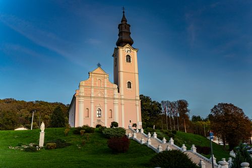 Free St. Patrick's Church in Pakrac with vibrant green surroundings and clear blue sky. Stock Photo