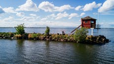 宁静的湖畔有一间木屋，人们在那里欣赏风景