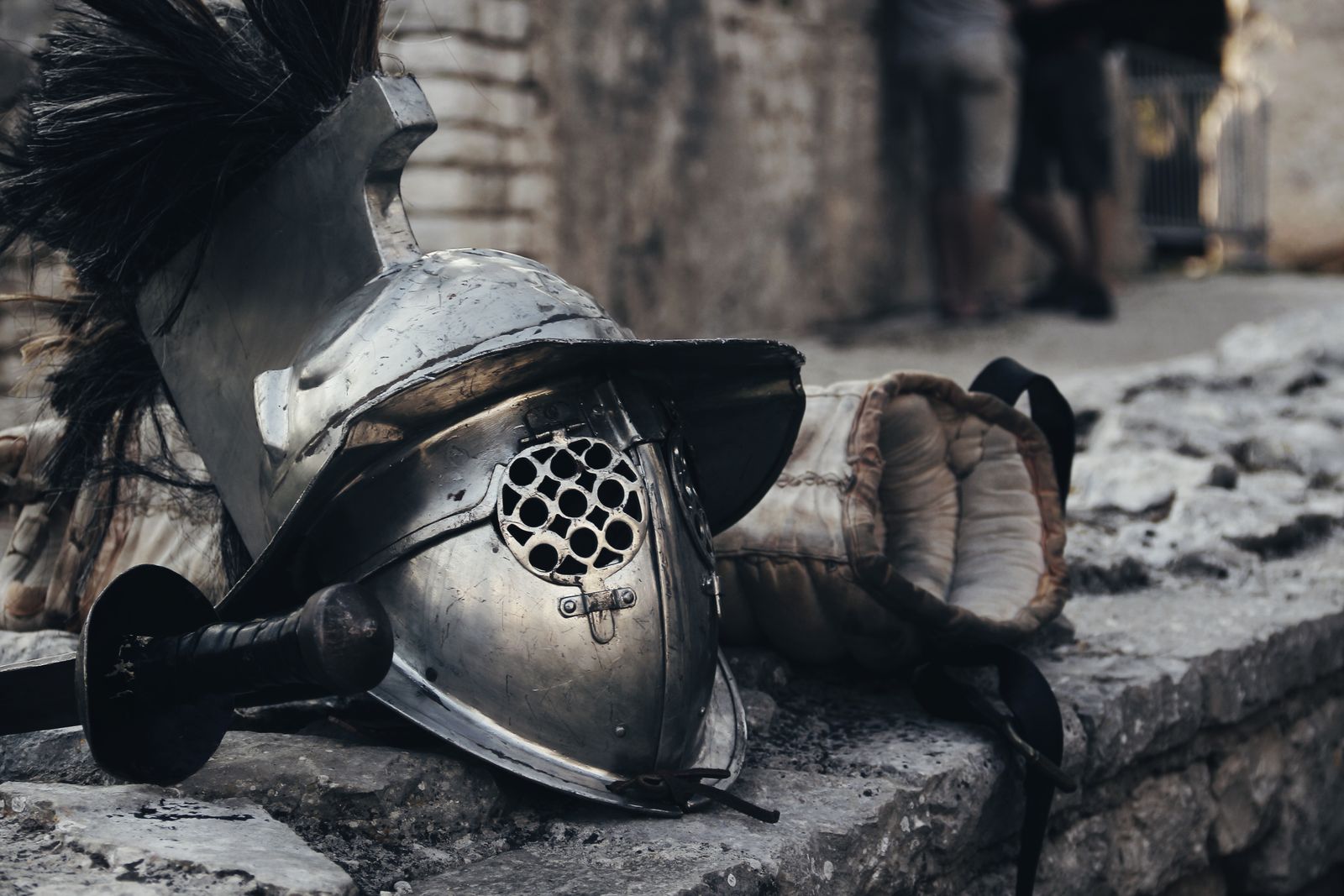 Medieval helmet, sword and glove resting against a stone wall, illustrative photo