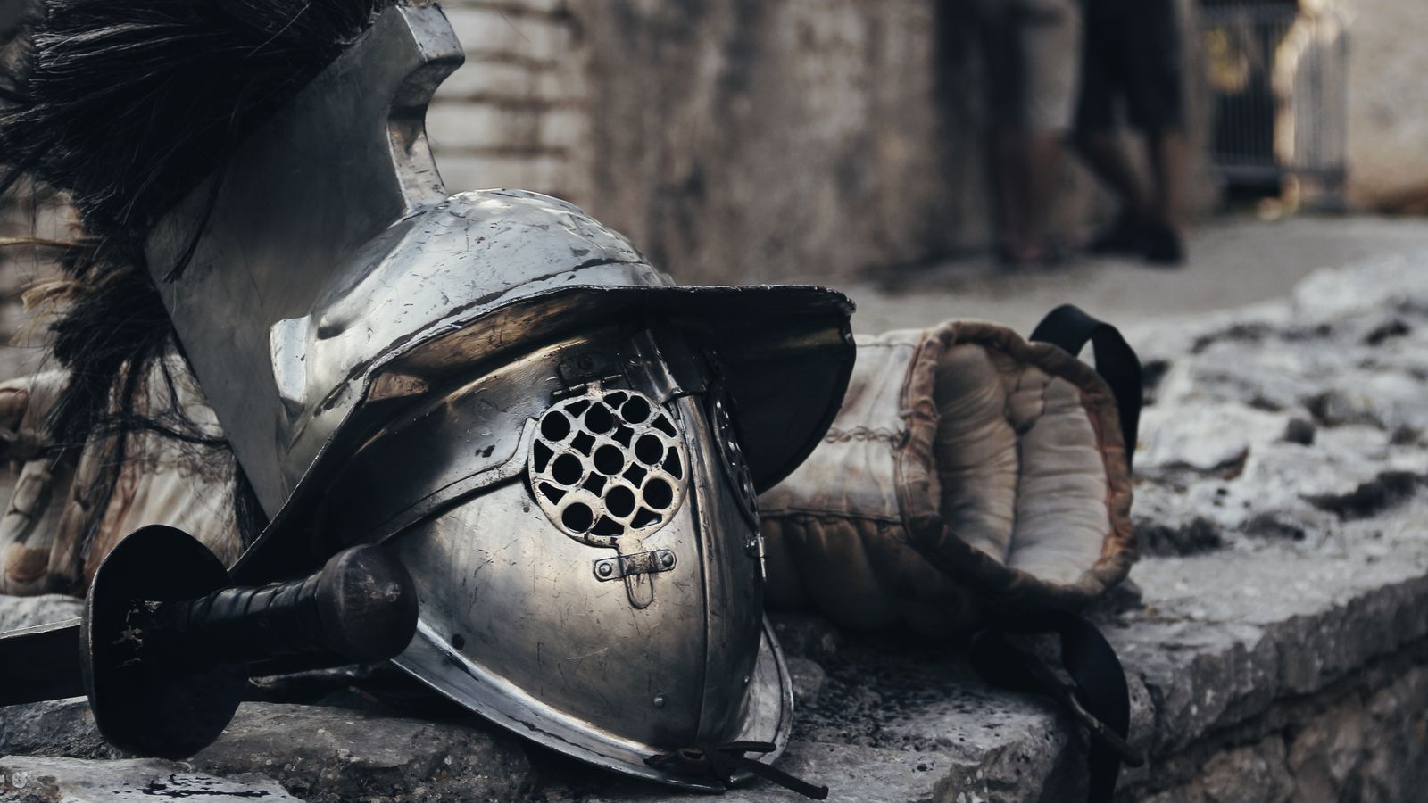 Medieval helmet, sword and glove resting against a stone wall, illustrative photo