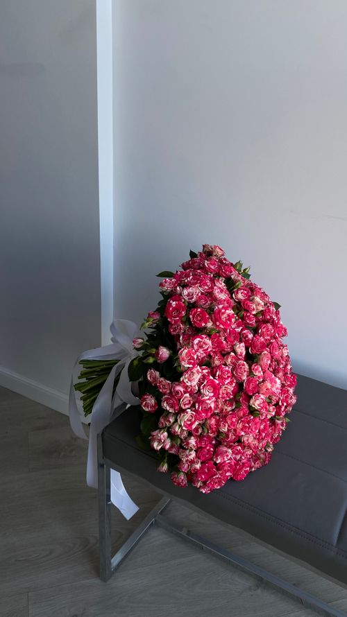 Free A stunning bouquet of vibrant pink roses placed elegantly on a modern bench indoors. Stock Photo