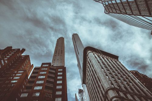 Free Looking up at towering skyscrapers in New York City under a dramatic, cloudy sky. Stock Photo