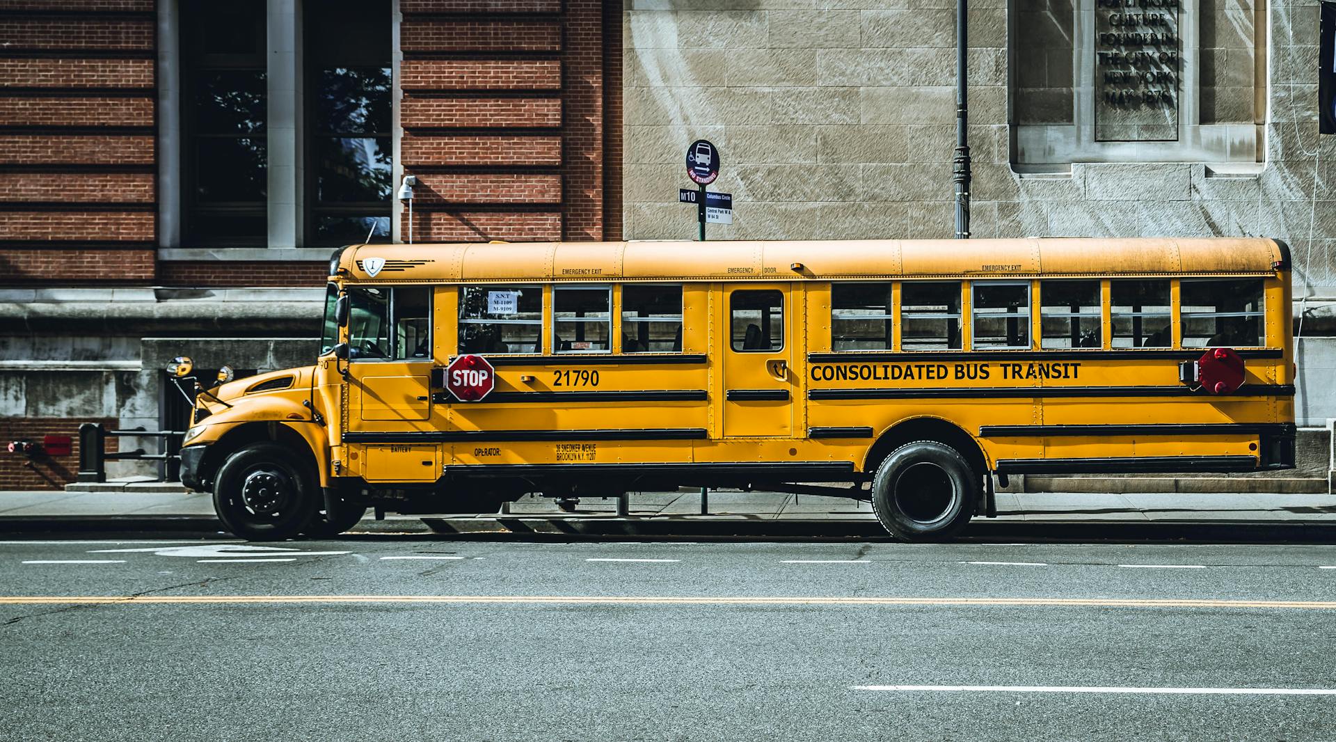 Yellow school bus parked in urban New York City street, showcasing iconic American transportation.