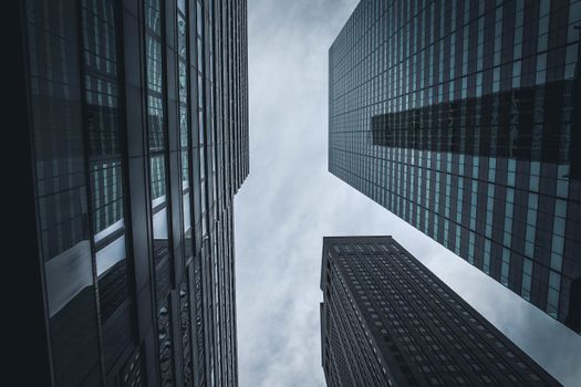 Upward view of New York City's skyscrapers against a cloudy sky, showcasing modern architecture.