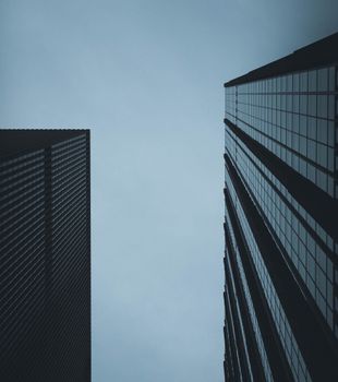 Dramatic low-angle shot of modern skyscrapers against a cloudy sky in New York City.