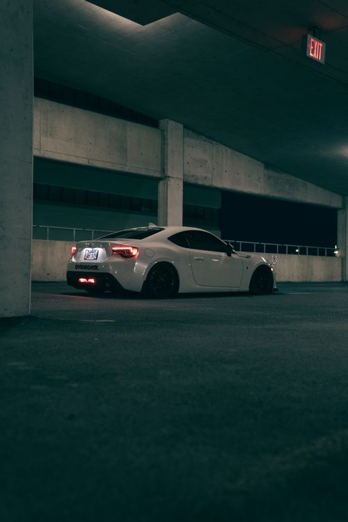 Free A white sports car parked in a dimly lit garage at night, showcasing modern design and style. Stock Photo