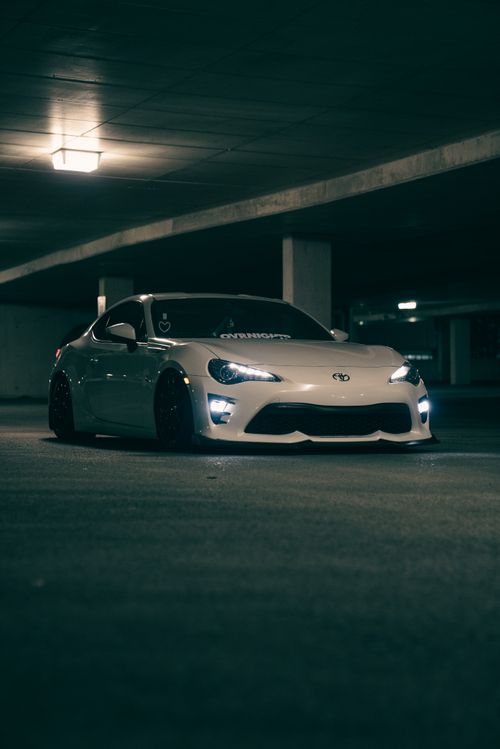 Free A sleek white sports car in a dimly lit underground parking garage, highlighting modern design. Stock Photo