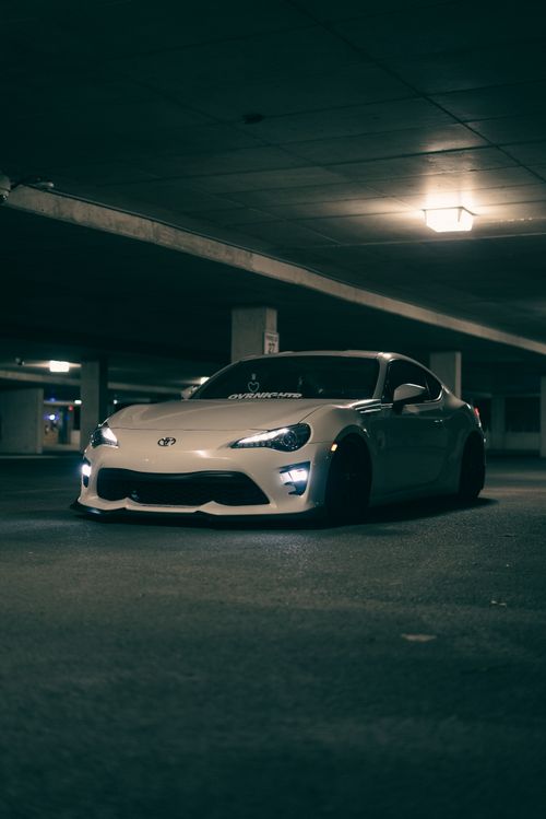 Free A stylish white sports car parked in a dimly lit underground garage, showcasing modern design. Stock Photo