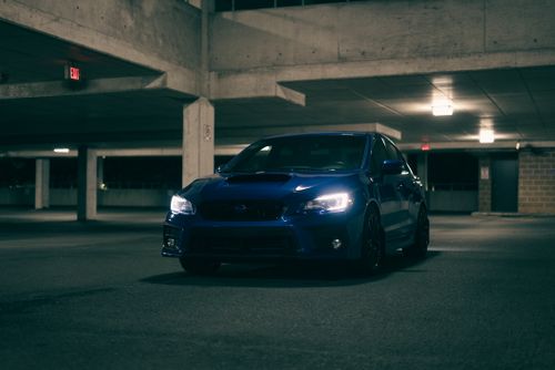 Free A sleek blue car parked in a dimly lit urban parking garage at night. Stock Photo
