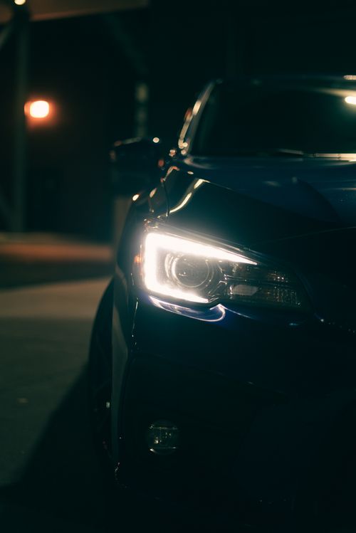 Free Close-up of a car headlight illuminated at night with a moody atmosphere. Stock Photo