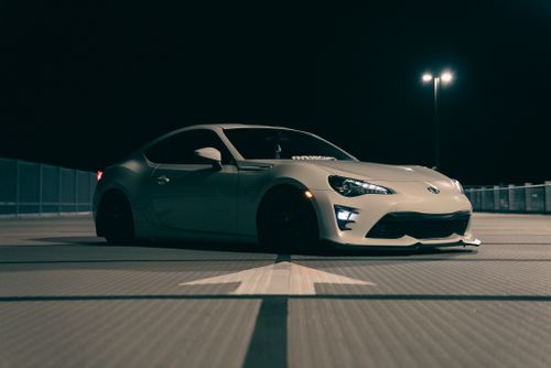 Free Stylish white sports car parked in a dimly lit parking lot at night. Stock Photo