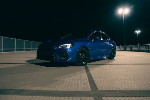 Free Blue sports car parked in urban setting under streetlights at night. Stock Photo