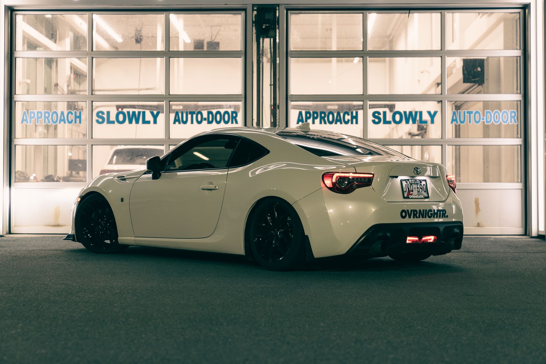 Side view of a stylish sports car in a well-lit garage. Night setting enhances modern vibe.