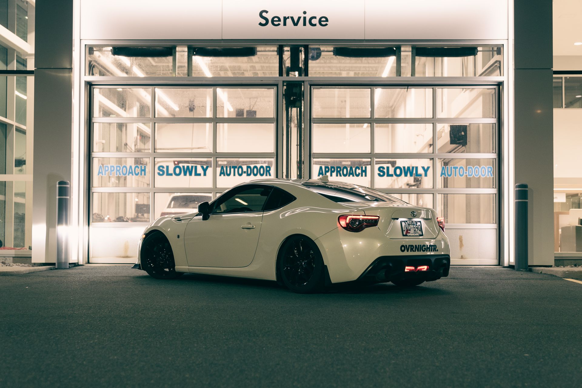 A sleek white sports car parked in a well-lit auto service area at night, highlighting modern design.