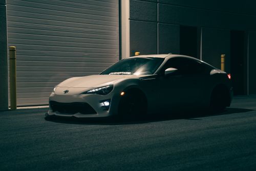 Free A sleek sports car is parked in an urban setting at night, featuring moody lighting and modern design. Stock Photo