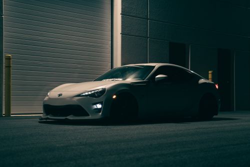 Free A stylish white sports car parked in an industrial area at night. Stock Photo