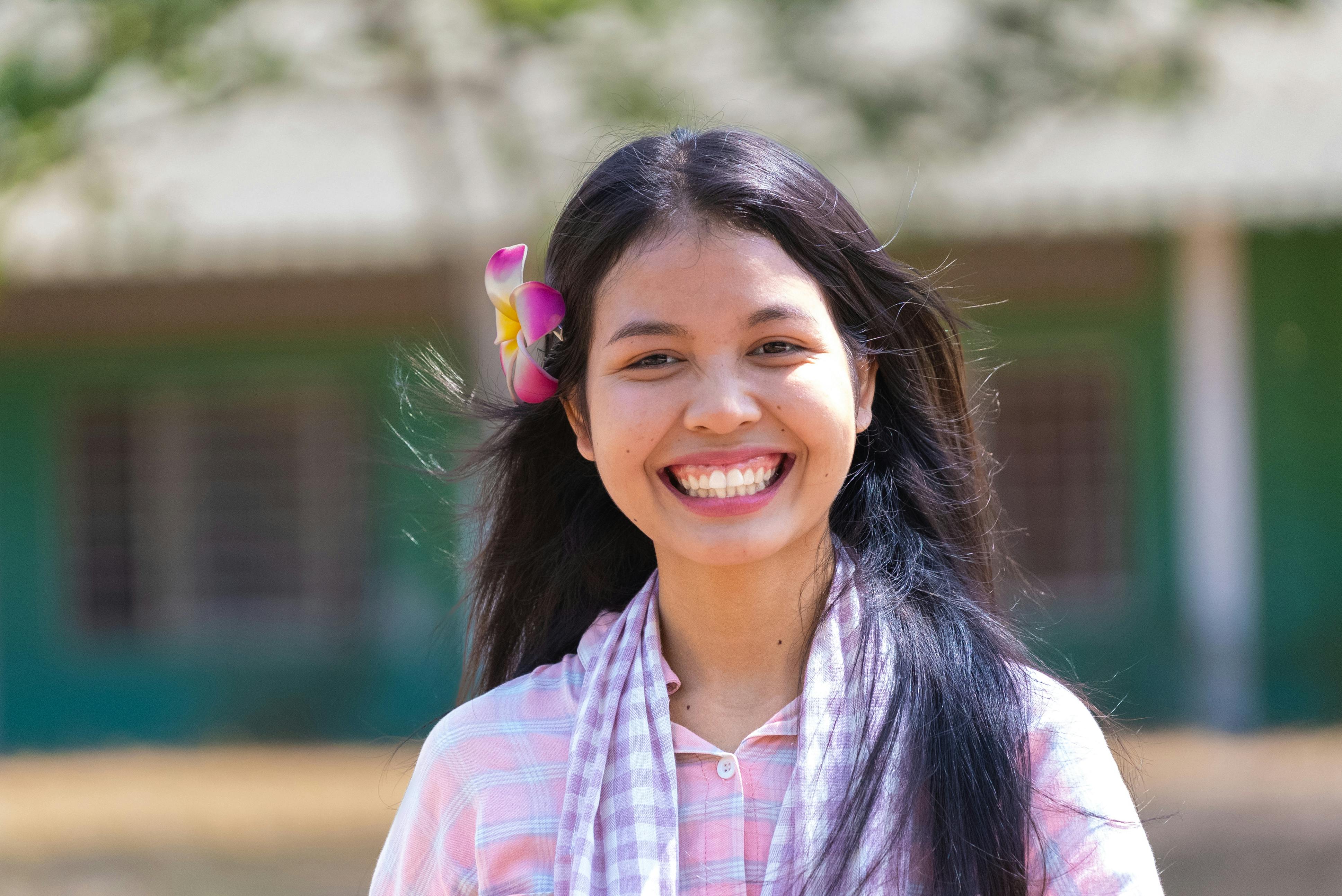 Zadarmo Mladá kambodžská žena sa vonku široko usmieva s kvetom vo vlasoch. Fotka z fotobanky