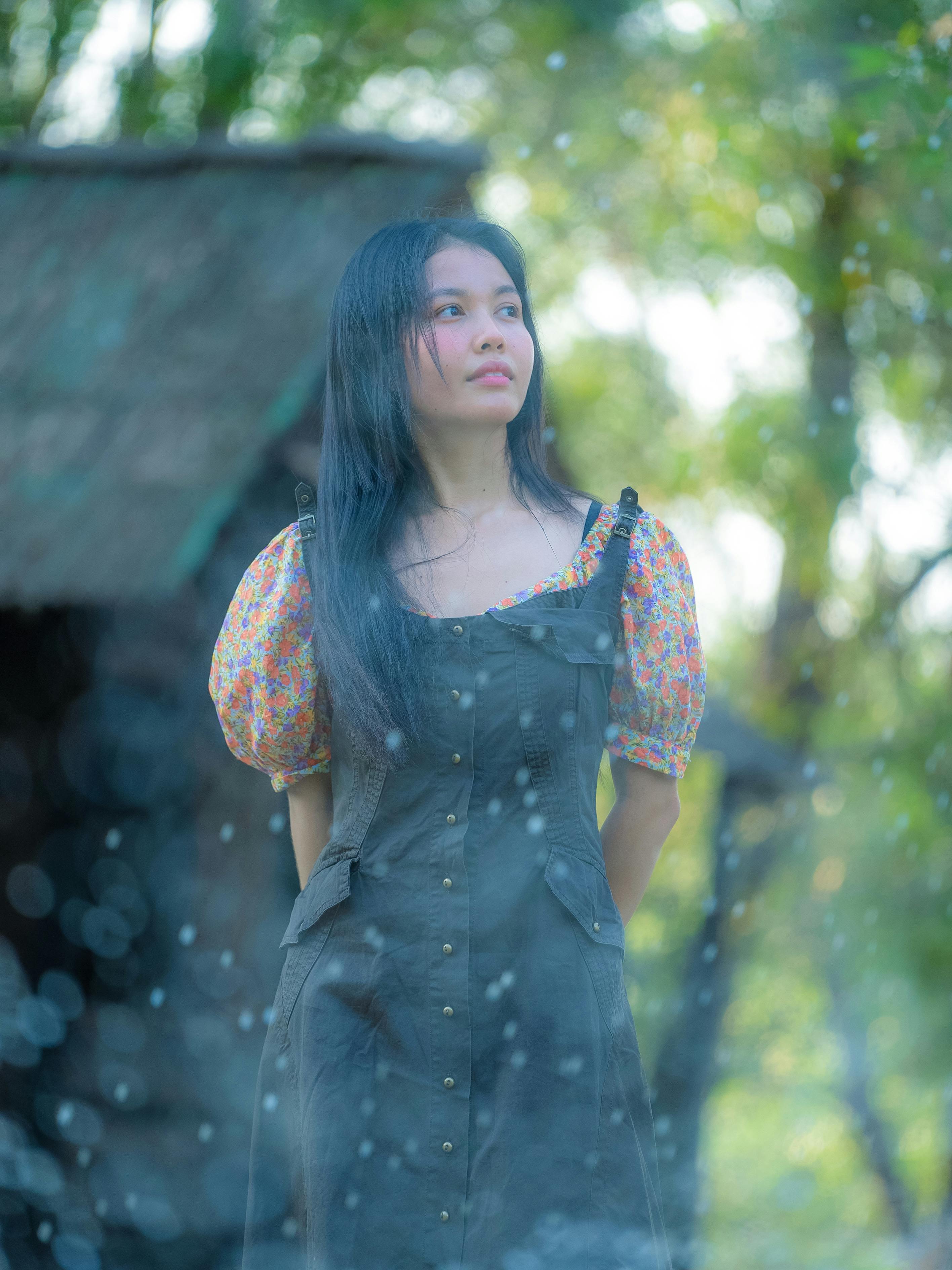 免费 一位身穿碎花连衣裙的年轻女子站在户外，周围环绕着大自然。 素材图片