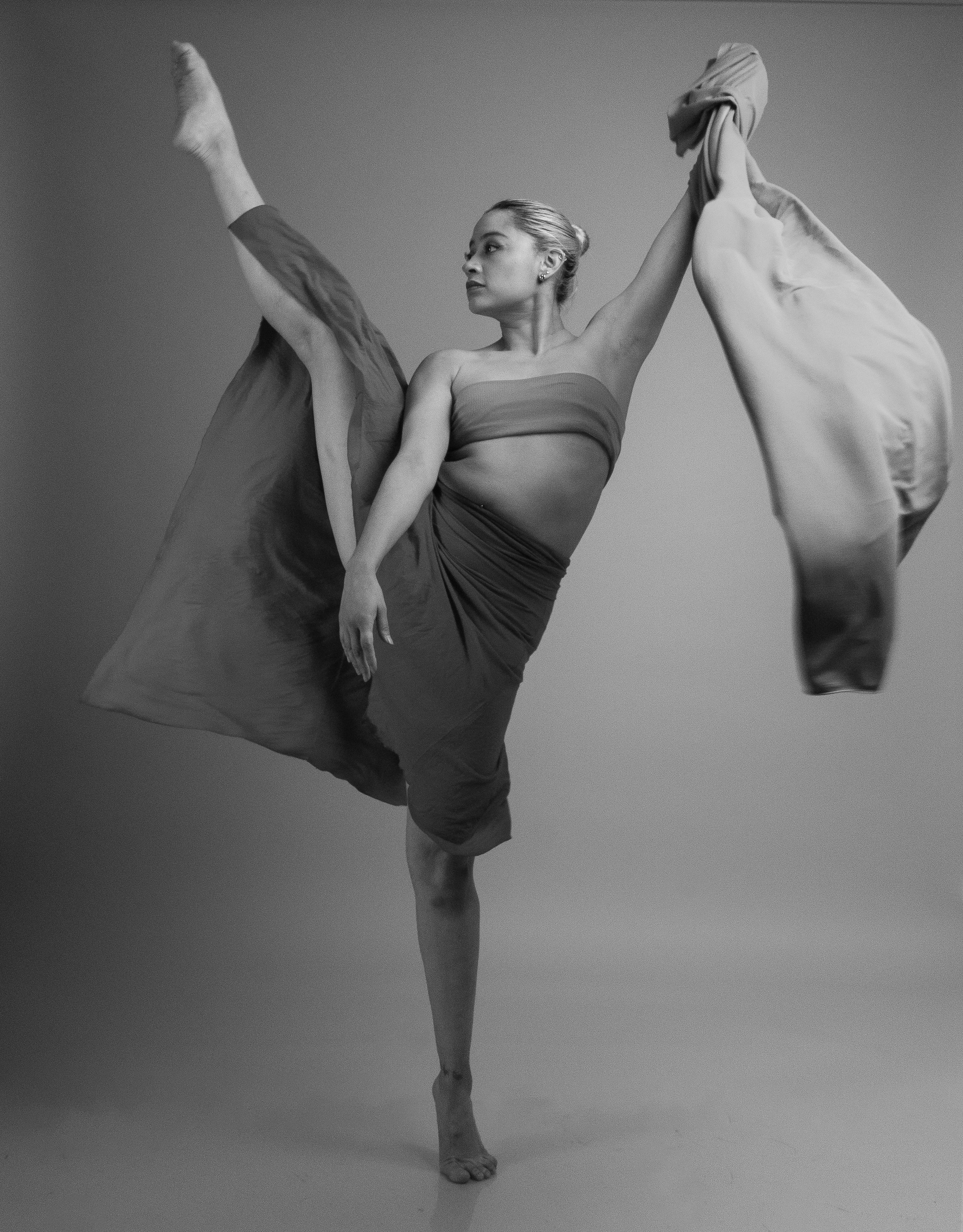 Black and white photo of a female dancer showcasing a stunning pose with flowing fabric.