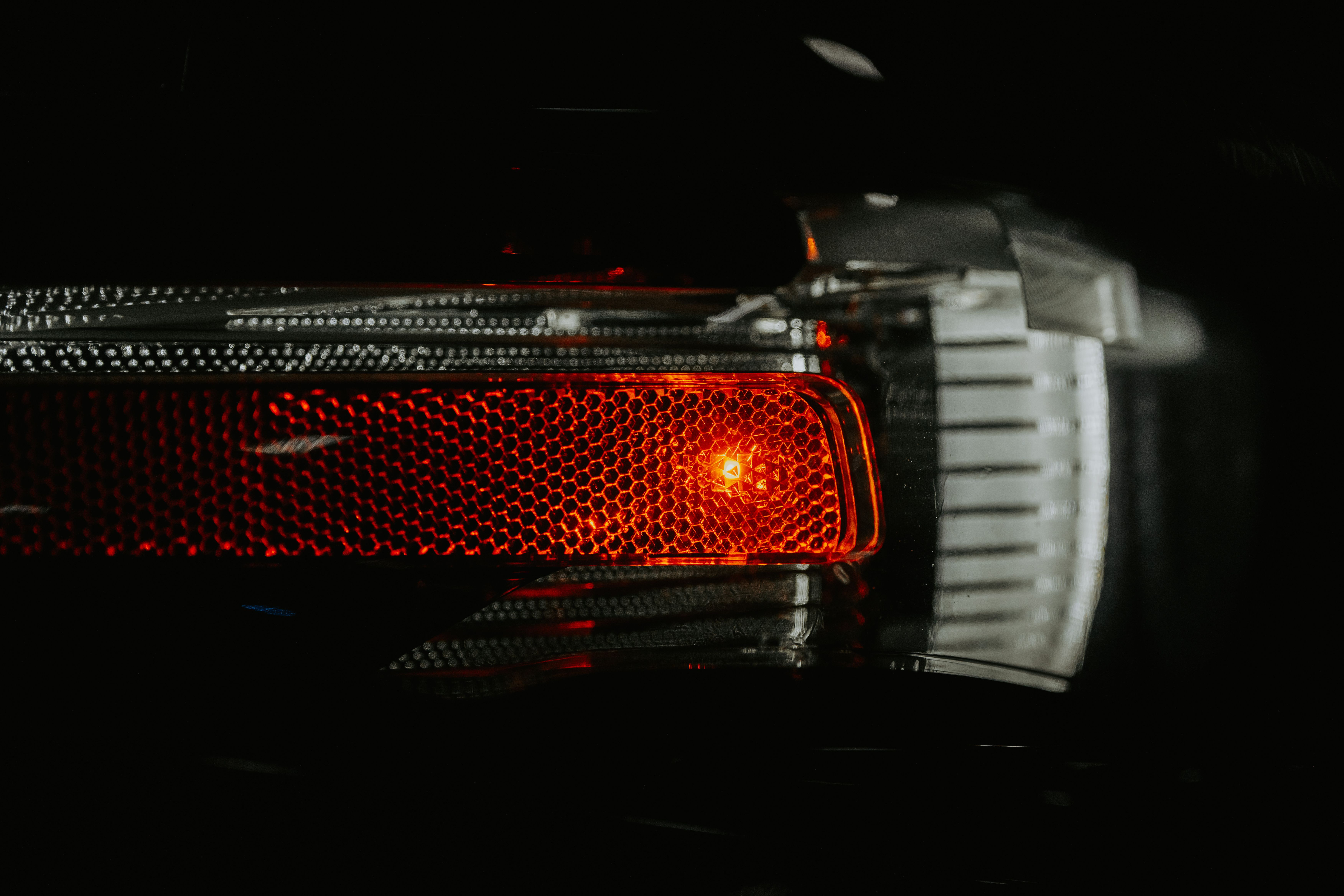 A detailed view of a car brake light with a textured lens illuminating in the dark.
