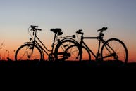 在色彩缤纷的日落天空映衬下，两辆自行车的轮廓凸显了户外冒险