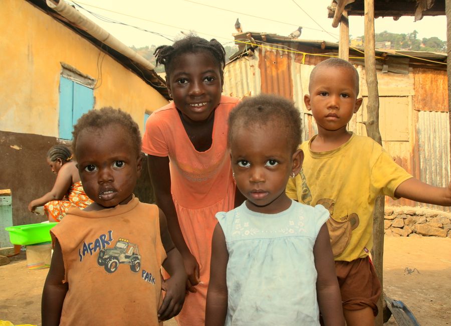 A group of children playing joyfully in a vibrant neighborhood in Freetown, Sierra Leone.