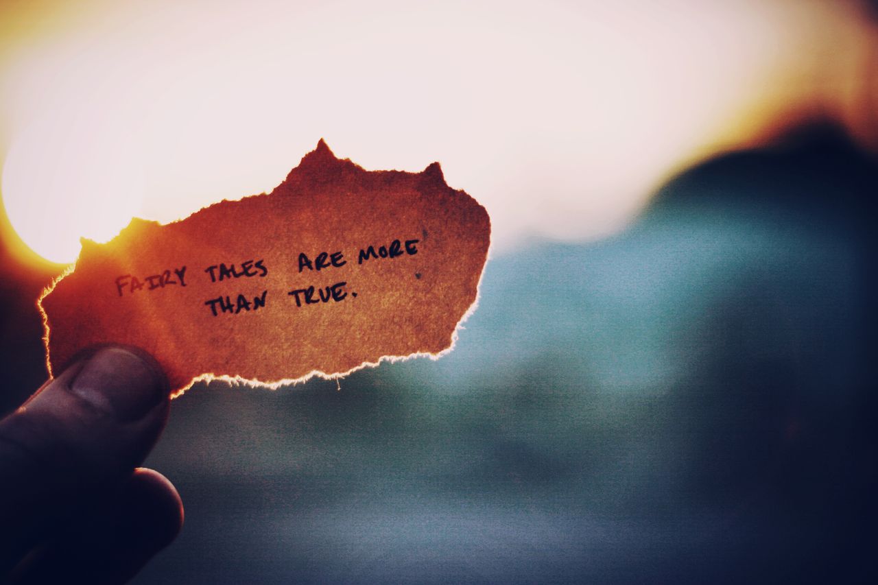close up of a hand holding paper with a motivational quote at sunset c